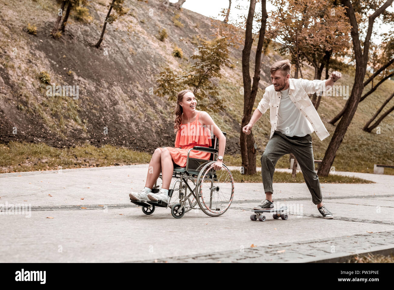 Mobilité girl looking at her boyfriend équitation penny board and smiling Banque D'Images