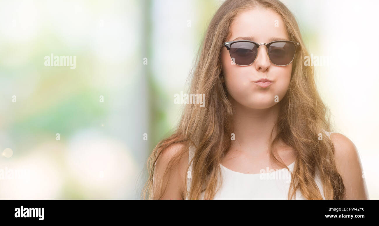 Jeune femme blonde portant des lunettes de soleil que quelques bouffées  joues avec drôle de visage. Bouche gonflé à l'air, l'expression fou Photo  Stock - Alamy