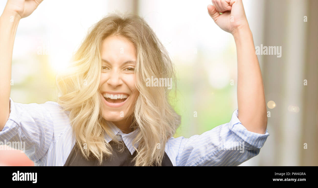 Jeune propriétaire de boutique Portant tablier noir heureux et excité célébrant la victoire l'expression de grand succès, la puissance, l'énergie et des émotions positives. Célèbre De nouveaux Banque D'Images