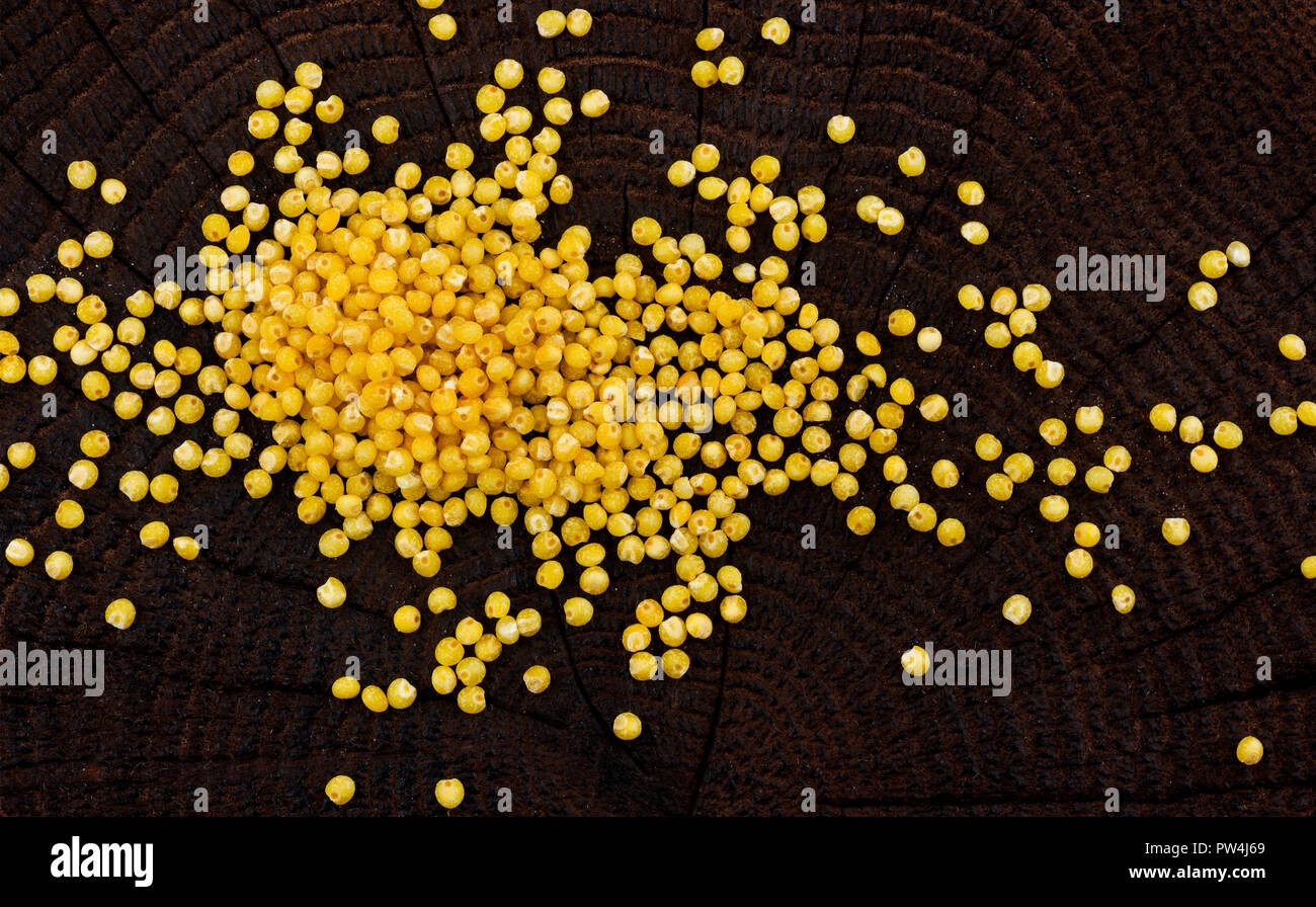 Tas de gruau de millet sur fond de bois noir, vue du dessus Banque D'Images