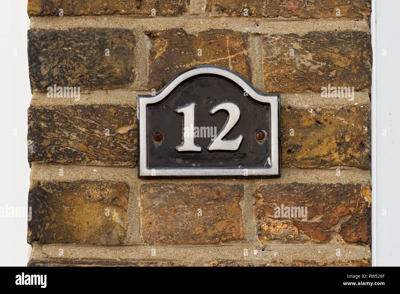 Chambre numéro 12 avec les douze sur une plaque en émail noir attaché à un mur de briques Banque D'Images