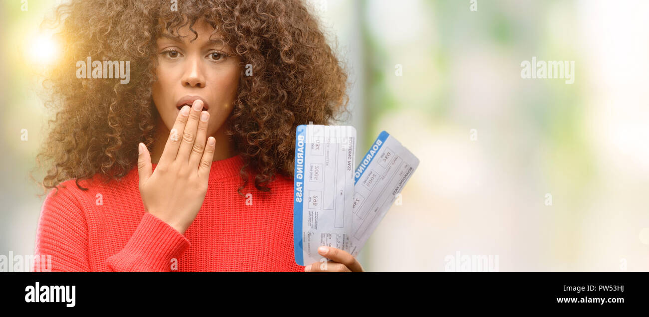 African American Woman holding airline boarding pass billets couvrir la bouche à part choqué avec honte pour erreur, expression de la peur, peur en silen Banque D'Images