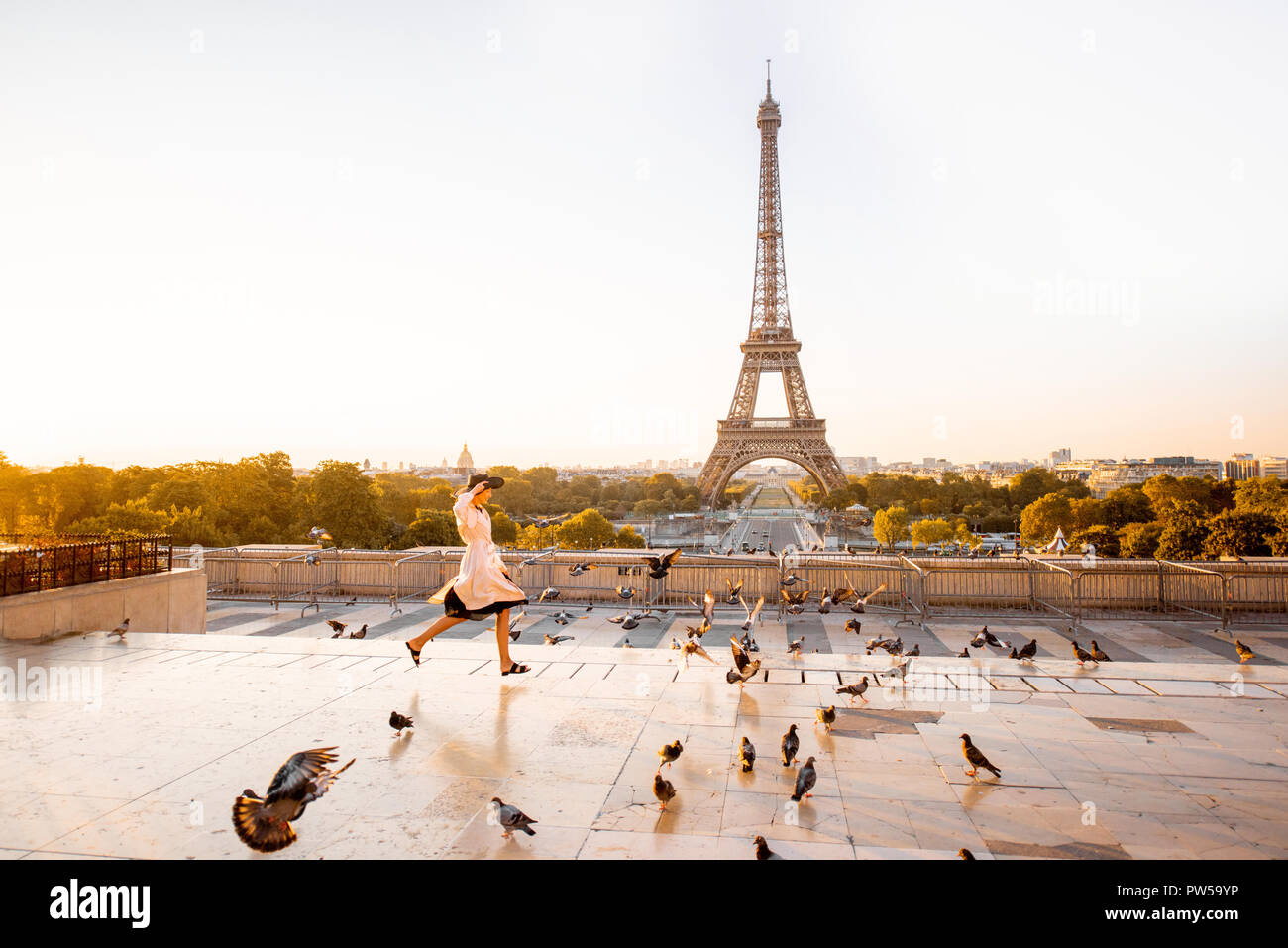 Femme d'exécution sur la célèbre place de disperser les pigeons avec très belle vue sur la Tour Eiffel tôt le matin à Paris Banque D'Images