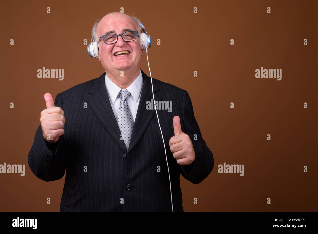 L'embonpoint senior businessman listening music with headphones Banque D'Images