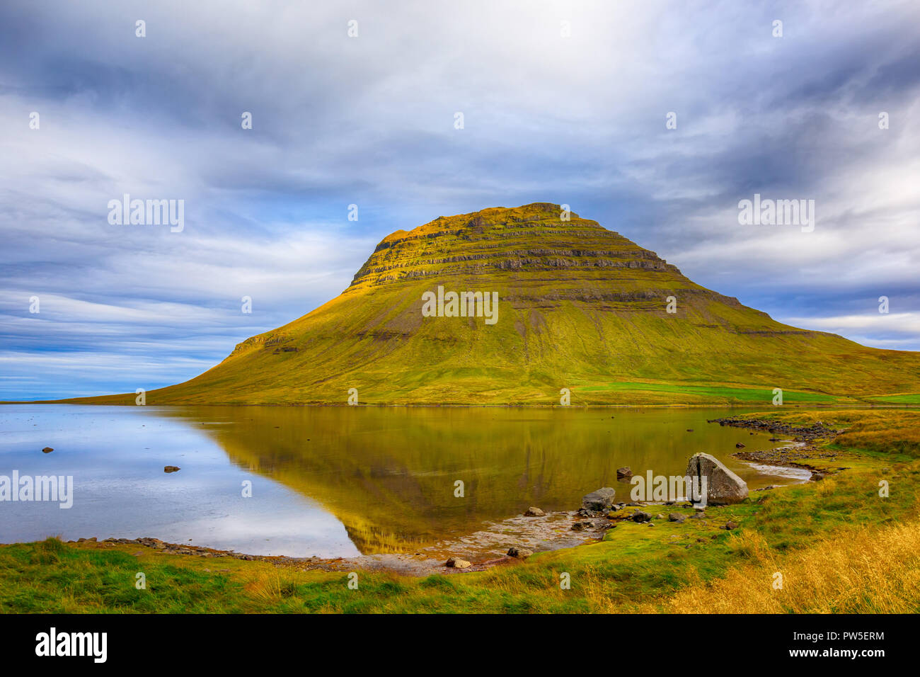 L'Islande est Kirksjefells avec montagne ciel dramatique et un reflet dans l'eau environnante encore comme la saison des changements et les verts tournez à jaune Banque D'Images