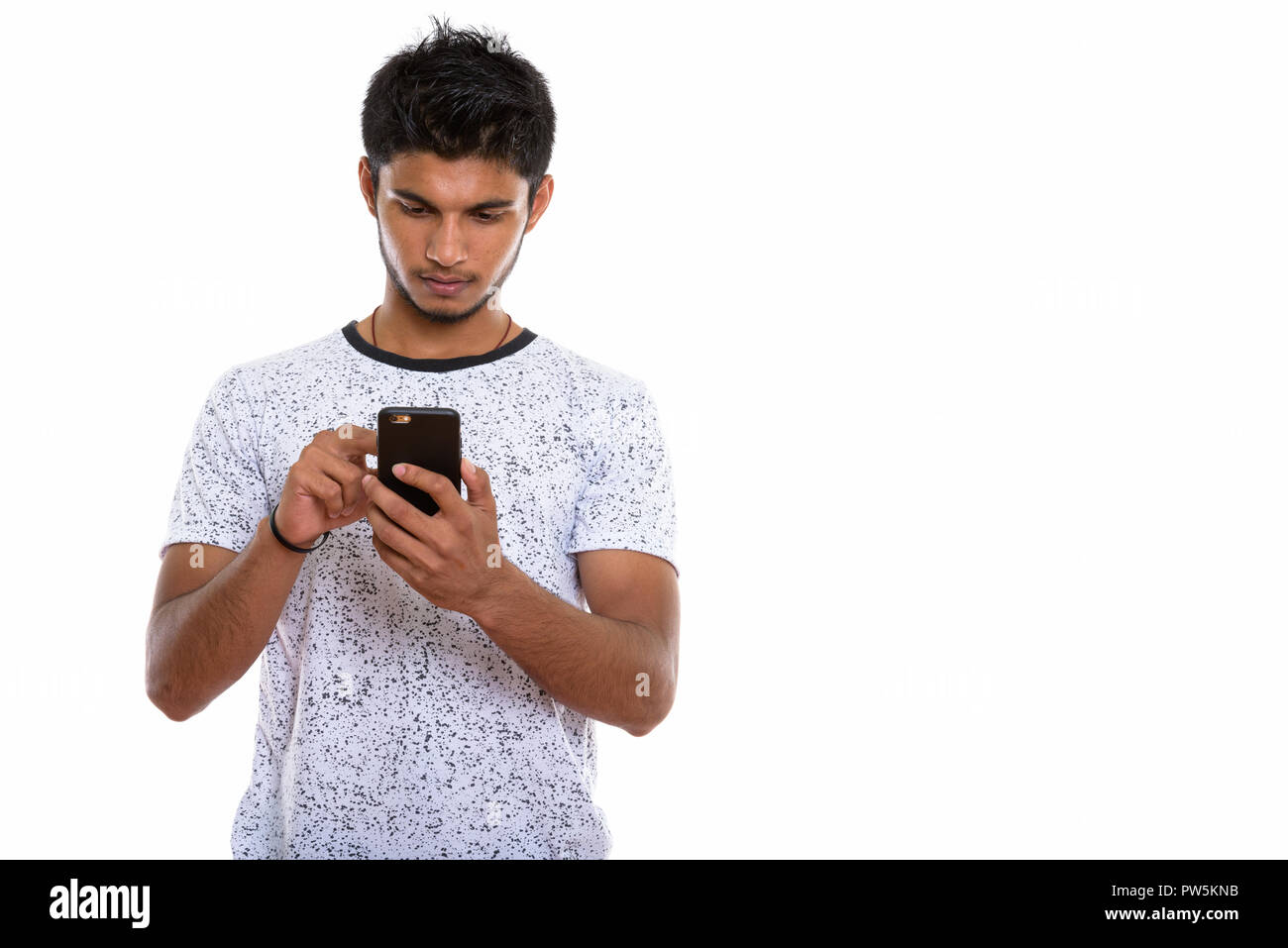 Studio shot of young handsome Indian man using mobile phone Banque D'Images