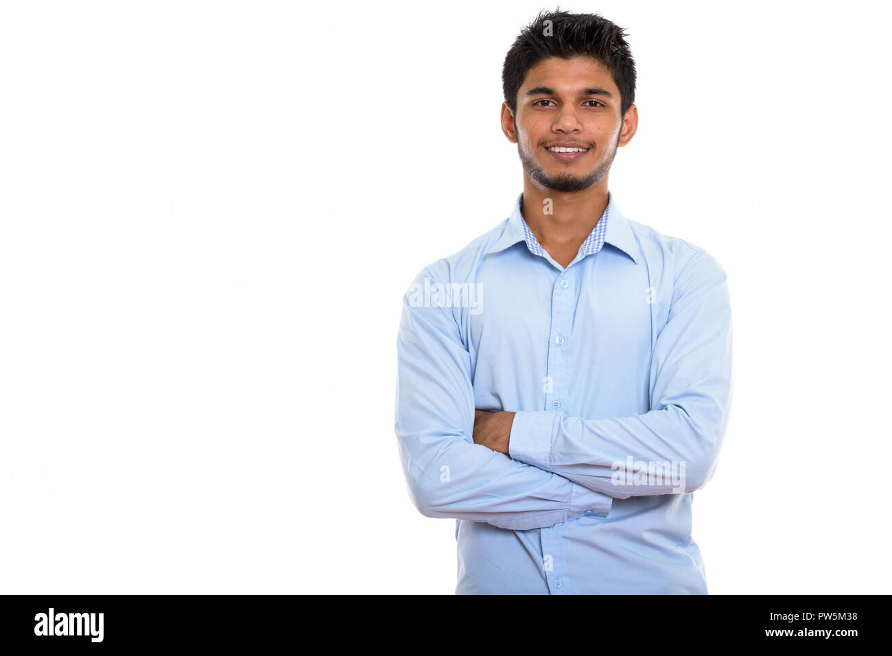 Studio shot of young happy Indian man smiling with arms crossed Banque D'Images