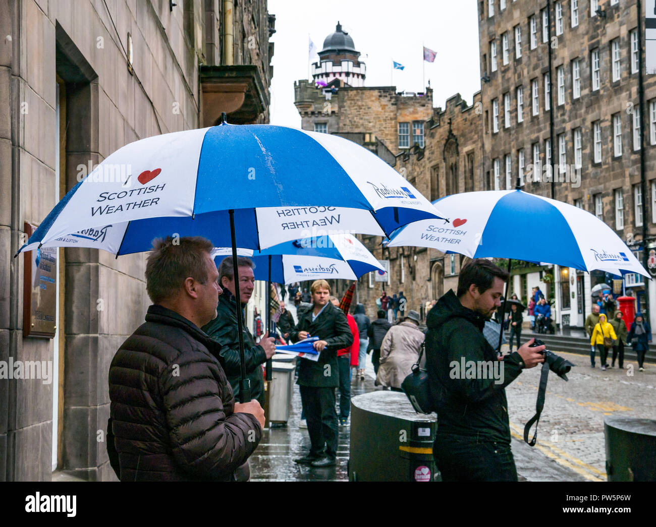 Royal Mile, Édimbourg, Écosse, Royaume-Uni, 12 octobre 2018. Royaume-uni : La pluie météo annonce l'arrivée de Storm Callum dans la capitale, mais n'a pas dissuader les touristes. Organiser de grands parasols touristes or avec coeur je météo écossais parasols de Radisson Hotel comme ils marchent dans le temps humide Banque D'Images