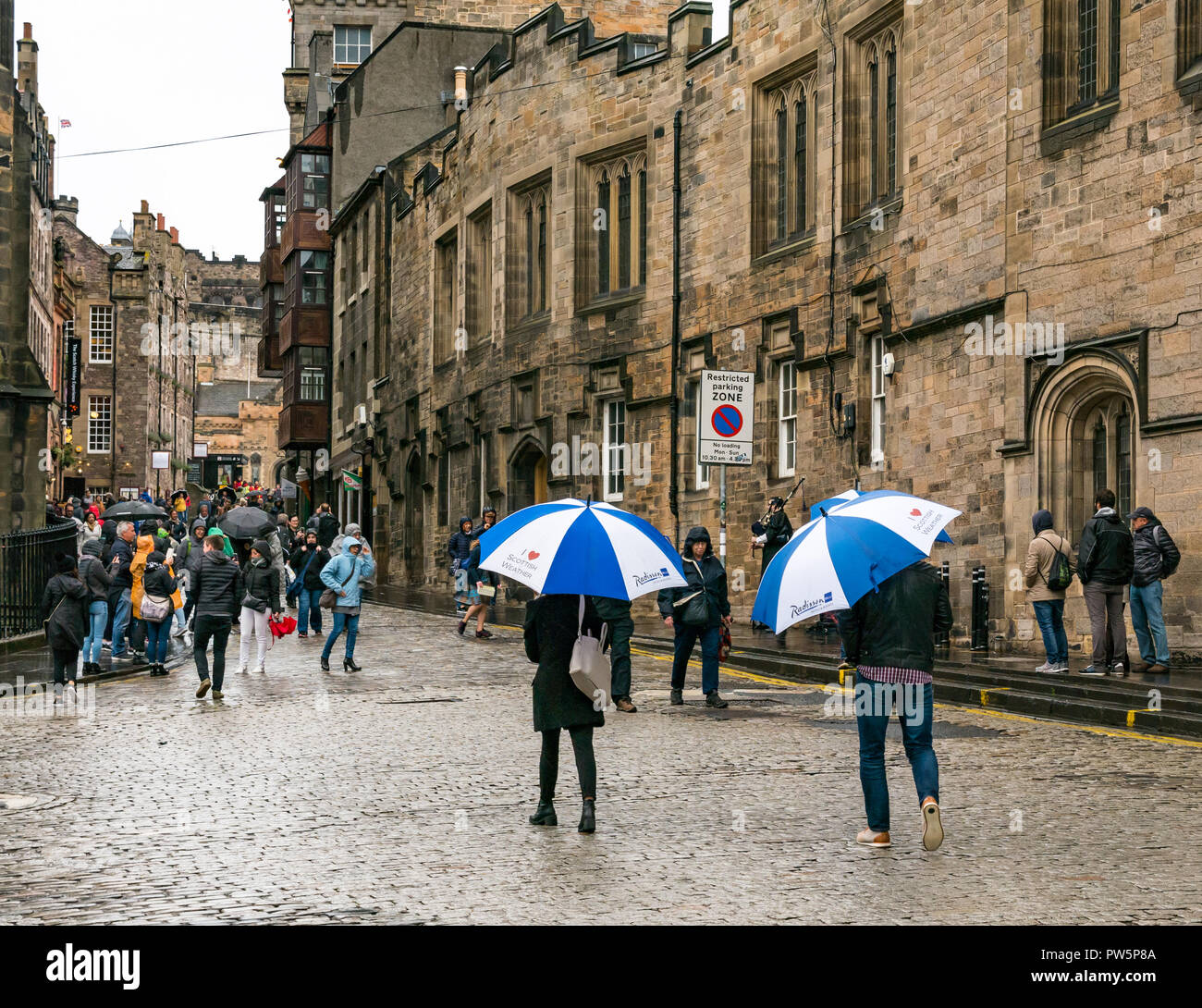 Royal Mile, Édimbourg, Écosse, Royaume-Uni, 12 octobre 2018. Royaume-uni : La pluie météo annonce l'arrivée de Storm Callum dans la capitale, mais n'a pas dissuader les touristes. Organiser de grands parasols touristes or avec coeur je météo écossais parasols de Radisson Hotel comme ils marchent dans le temps humide Banque D'Images