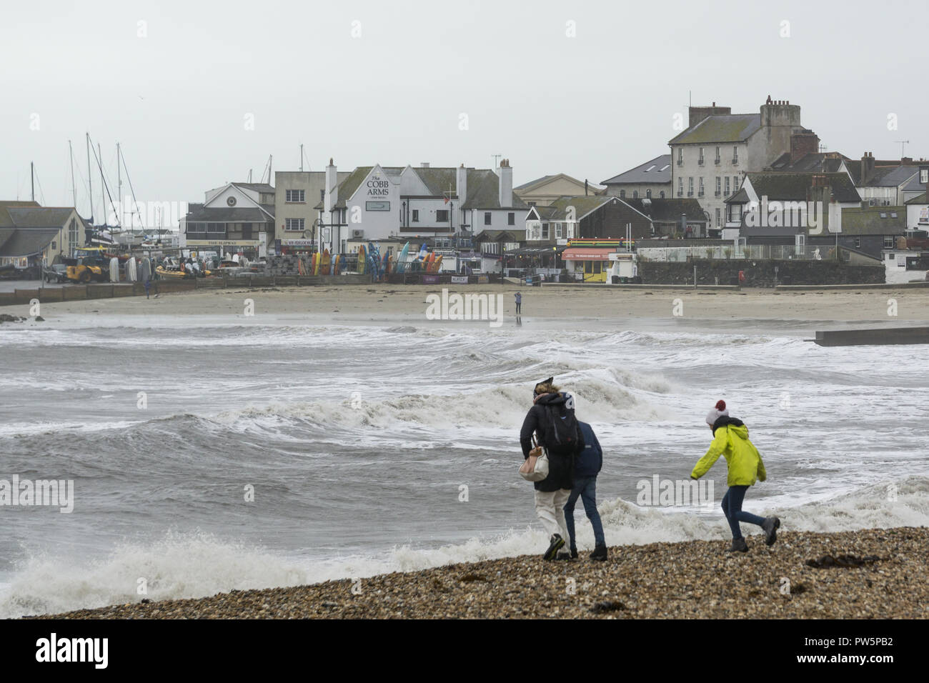 Lyme Regis, dans le Dorset. 12 octobre 2018. Les restes de la tempête Callum se font toujours sentir sur la jolie ville côtière de Lyme Regis dans le Dorset, vendredi après-midi. Les visiteurs et les gens braves l'extrême des vents violents et la pluie sur la plage et de la célèbre Cobb. Des vagues aussi hautes que un bus à impériale batter les défenses côtières et jeter du sable et galets à travers la promenade. Credit : Wayne Farrell/Alamy Live News Banque D'Images