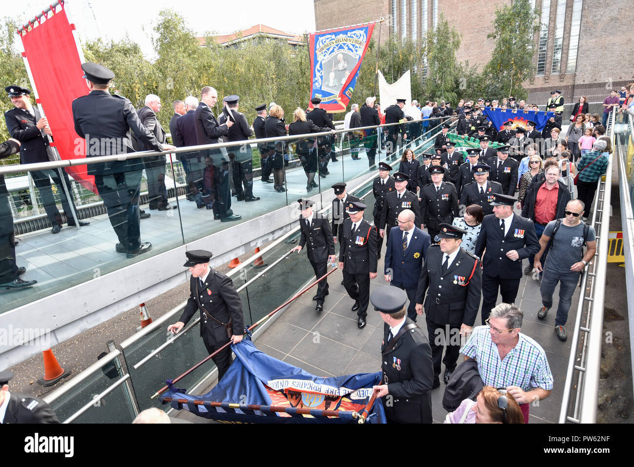 Londres, Royaume-Uni. 13 octobre 2018. Après une cérémonie de dépôt à l'échelle nationale à la mémoire des pompiers à côté de la Cathédrale St Paul, à la mémoire de pompiers morts représentant chaque service d'incendie au Royaume-Uni, les membres de l'Union européenne de lutte contre l'incendie (FBU) prendre part à un défilé officiel à travers le Millennium Bridge suivi d'un service à la cathédrale de Southwark pour commémorer le centenaire de la création de la FBU. Les activités sont les plus importantes jamais cérémonie pour les pompiers tués en service. Crédit : Stephen Chung / Alamy Live News Banque D'Images