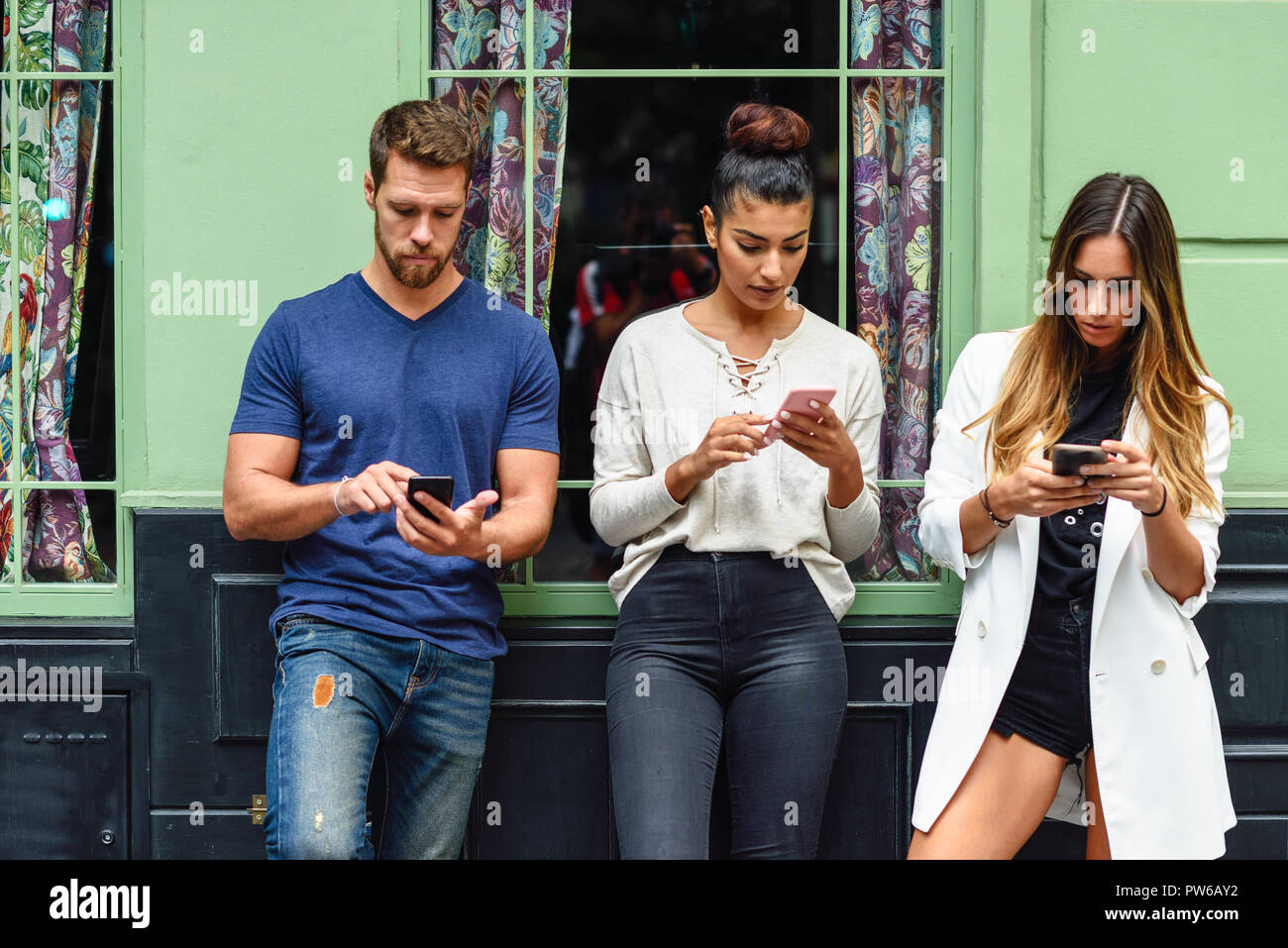 Groupe multiracial de personnes regardant le téléphone intelligent, les concepts au sujet de la technologie et les jeunes de la toxicomanie Banque D'Images