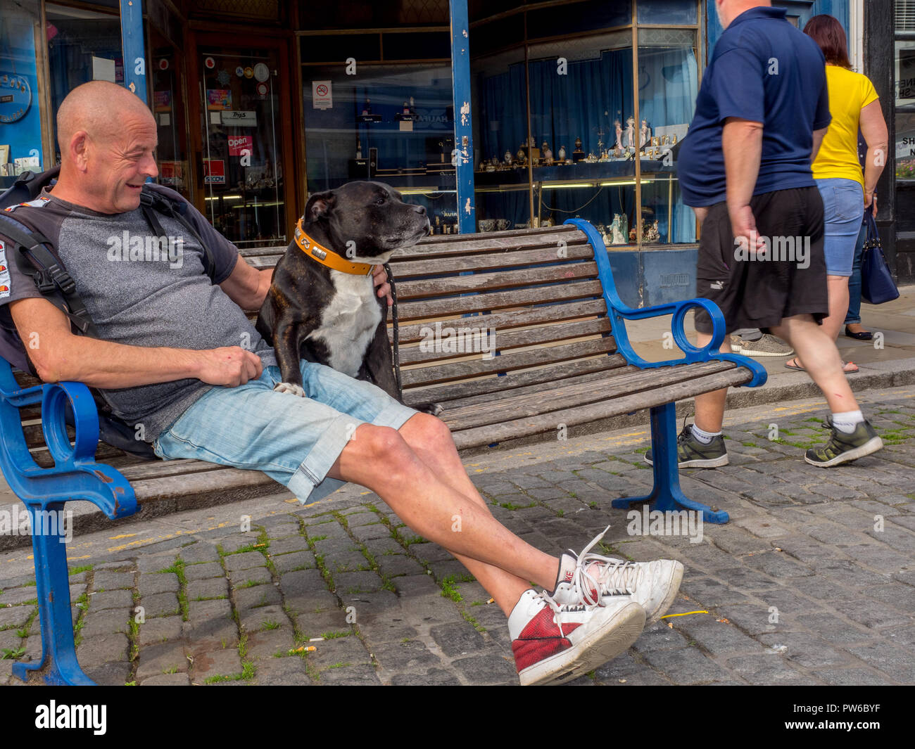 St un homme avec son chien sur un banc à Sheerness Hight Street, Kent. Banque D'Images