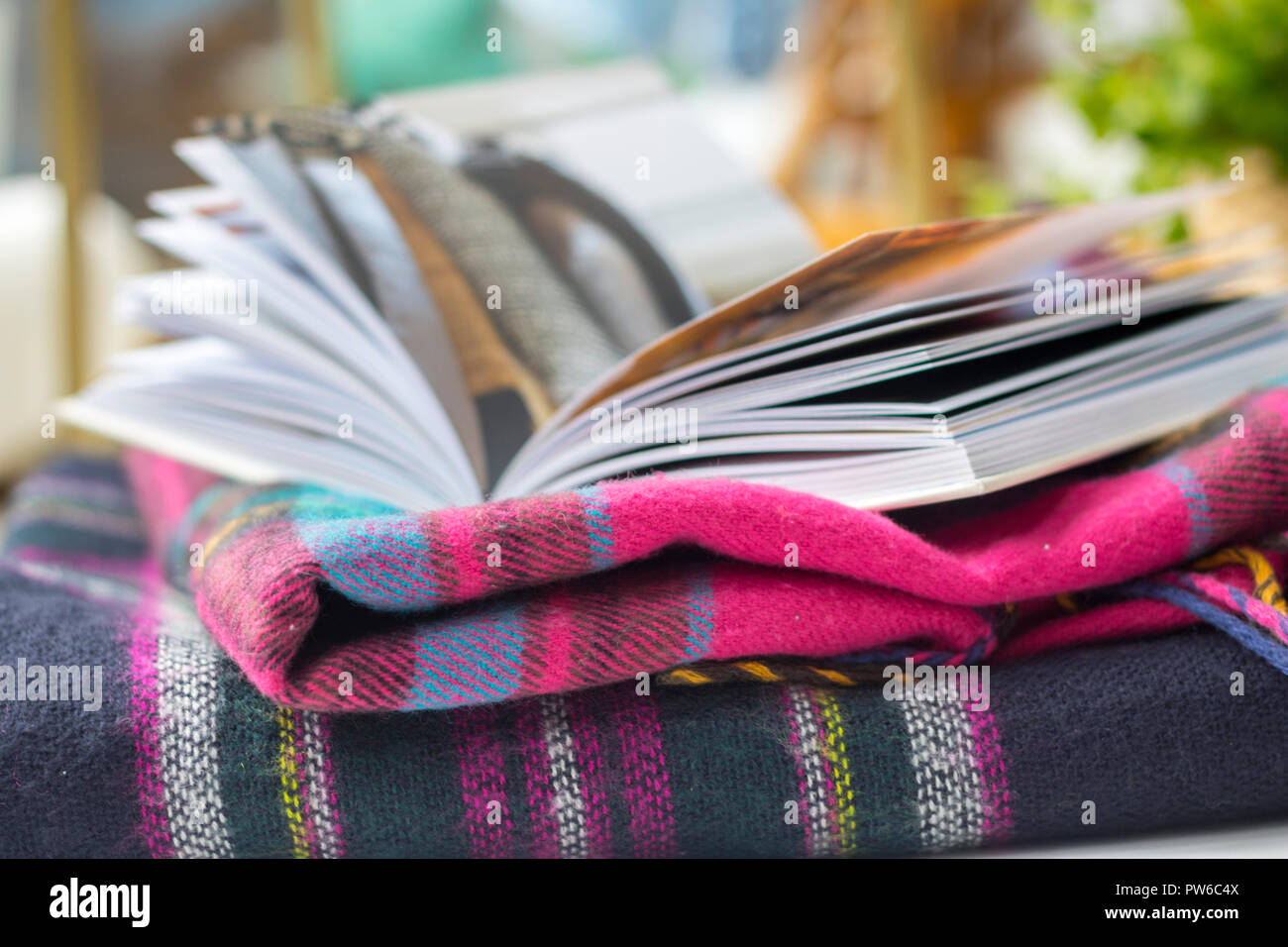 Couverture tartan livre ouvert sur une table de jardin à l'extérieur des maquettes, flatlay concept timeout, hygge, style de vie facile, meilleure vie brouillée détendue relaxant Banque D'Images