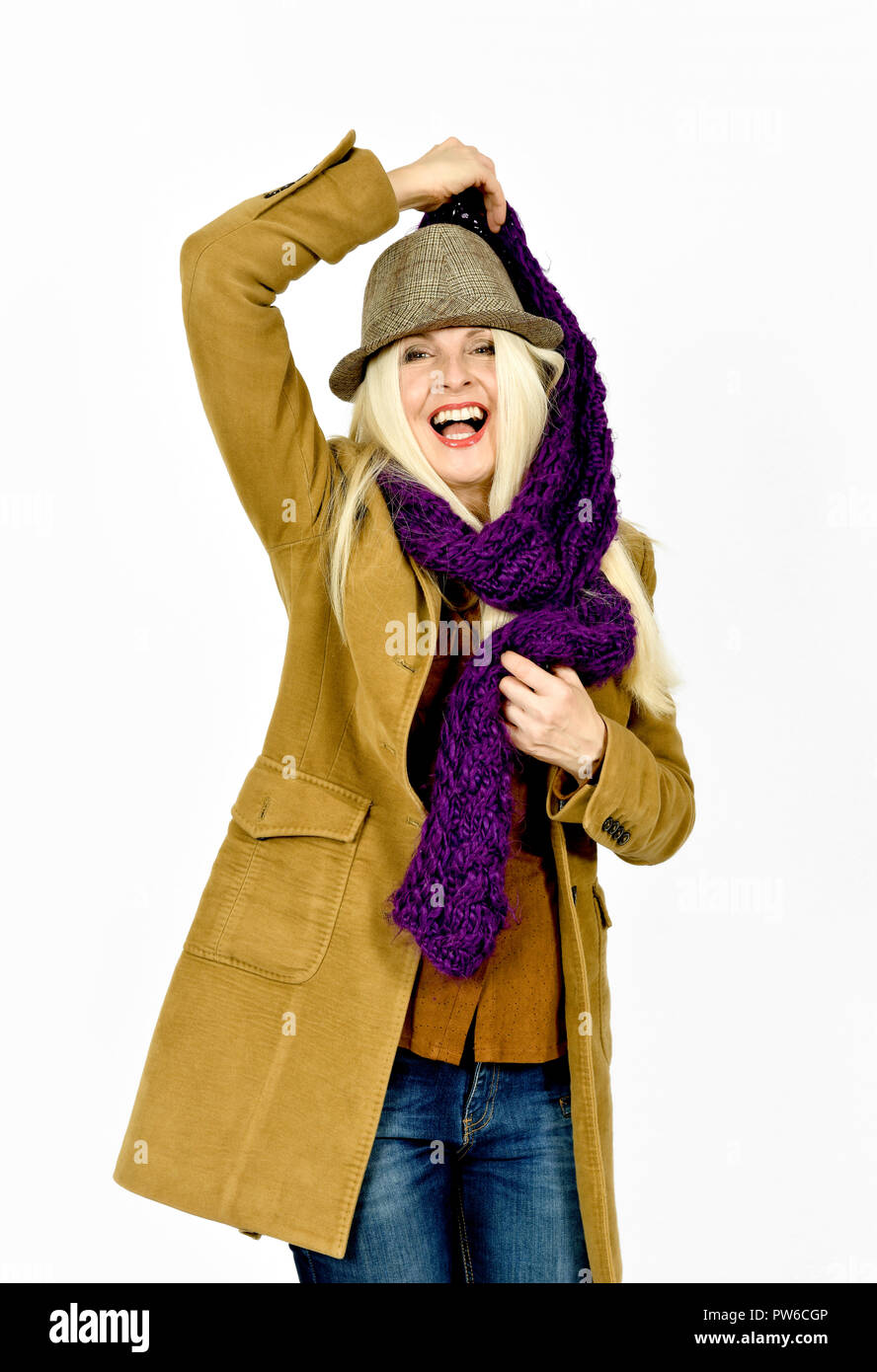 Jolie femme caucasienne en manteau d'hiver et de rire tout en mettant un chapeau foulard mauve sur Banque D'Images