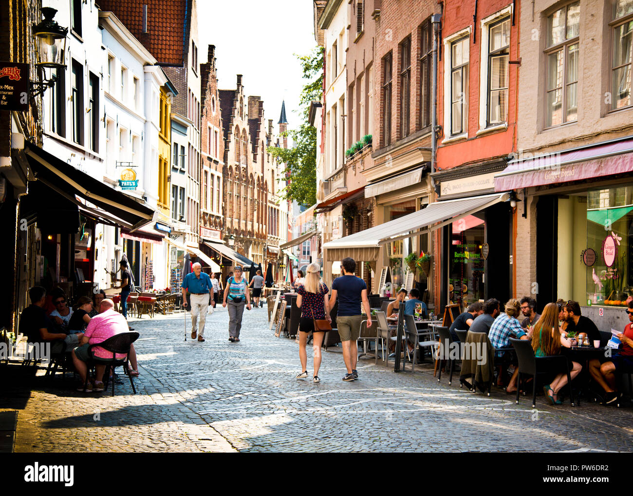 Jeunes et vieux couples marchant dans la rue pavée avec des cafés et des boutiques des deux côtés de la zone piétonne seulement, bruges Belgique, Europe. Banque D'Images