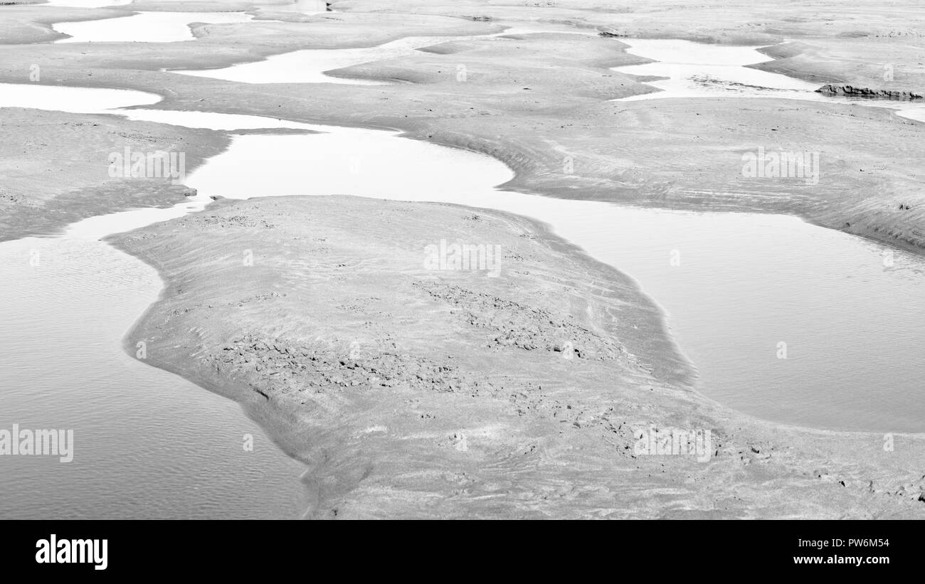 Les flaques laissées sur la plage de Bude Cornwall après la marée haute en noir et blanc Banque D'Images