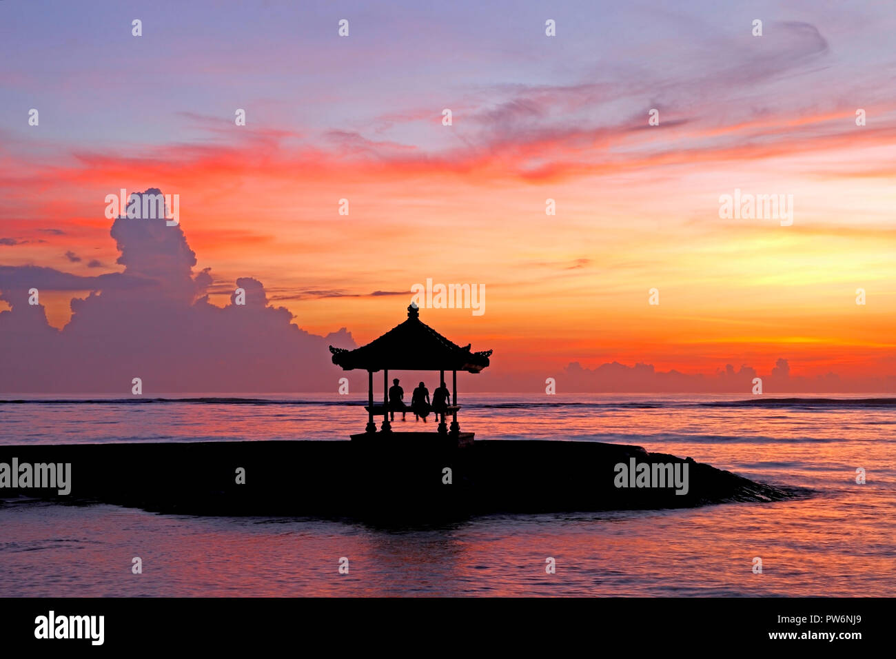 Trois personnes assises dans une pagode balinais sur la plage de Sanur, au lever du soleil, la plage de Sanur, Bali, Indonésie Banque D'Images