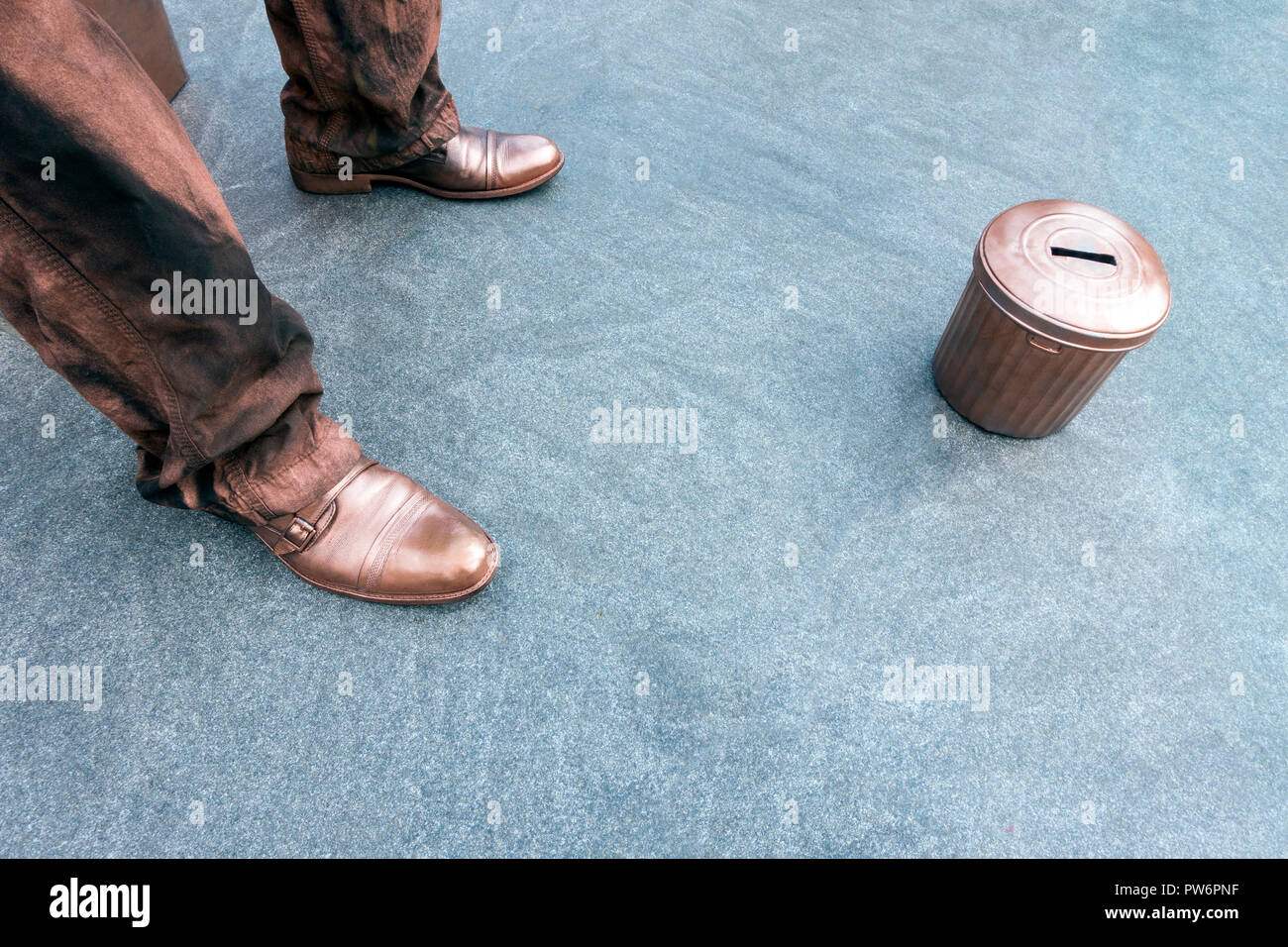 Artiste de rue avec des vêtements de bronze sur trottoir avec corbeille argent tasse Banque D'Images
