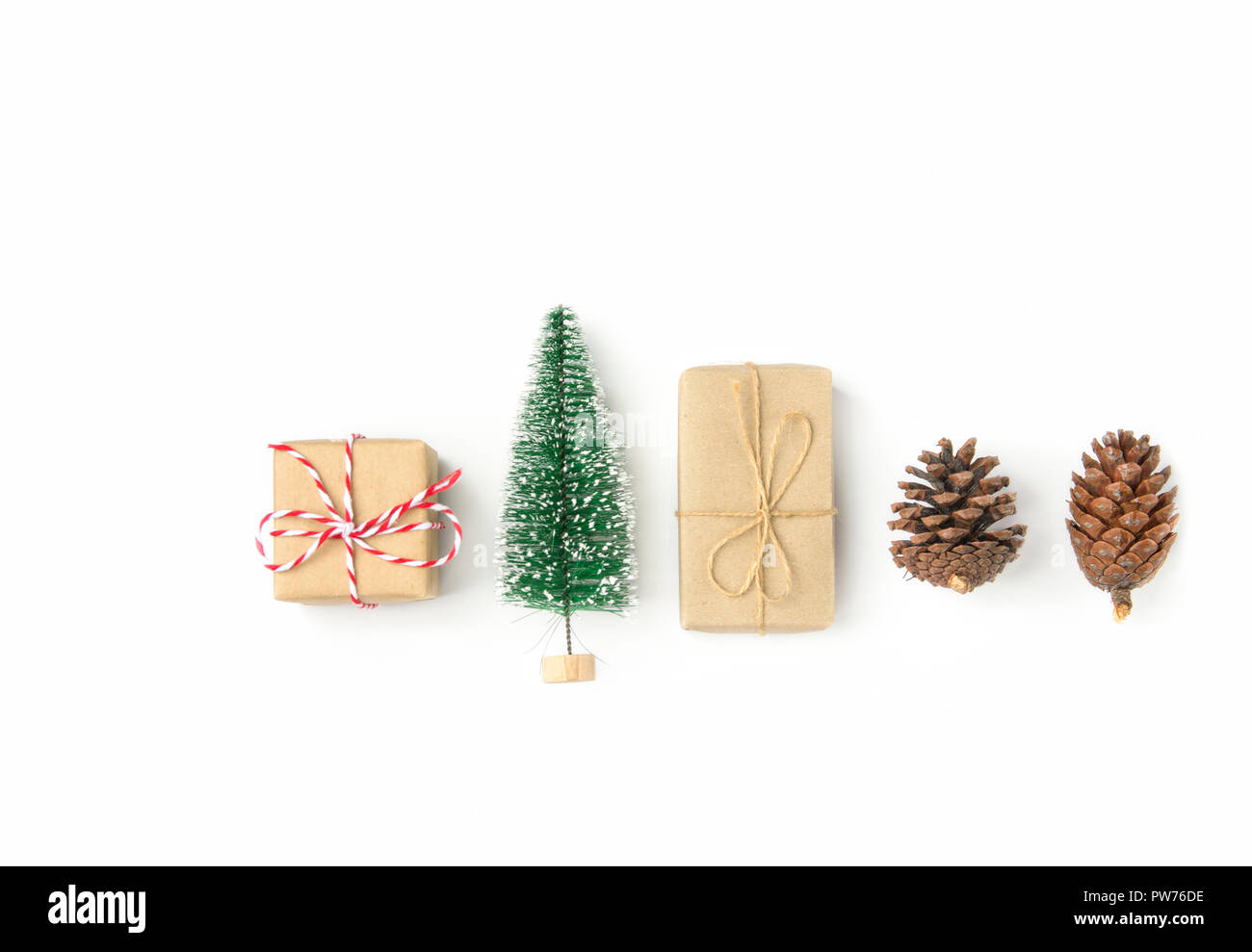Boîtes cadeau enveloppé dans du papier craft arbre de Noël pomme de pin disposées en ligne sur fond blanc solide. Knolling mise à plat. Nouvelle année présente maison de pr Banque D'Images