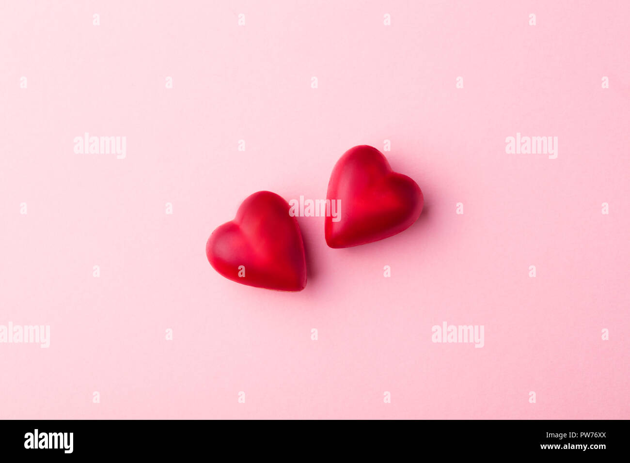 Deux bonbons au chocolat coeur rose sur fond de papier pastel. Vue d'en haut. Copy space Banque D'Images