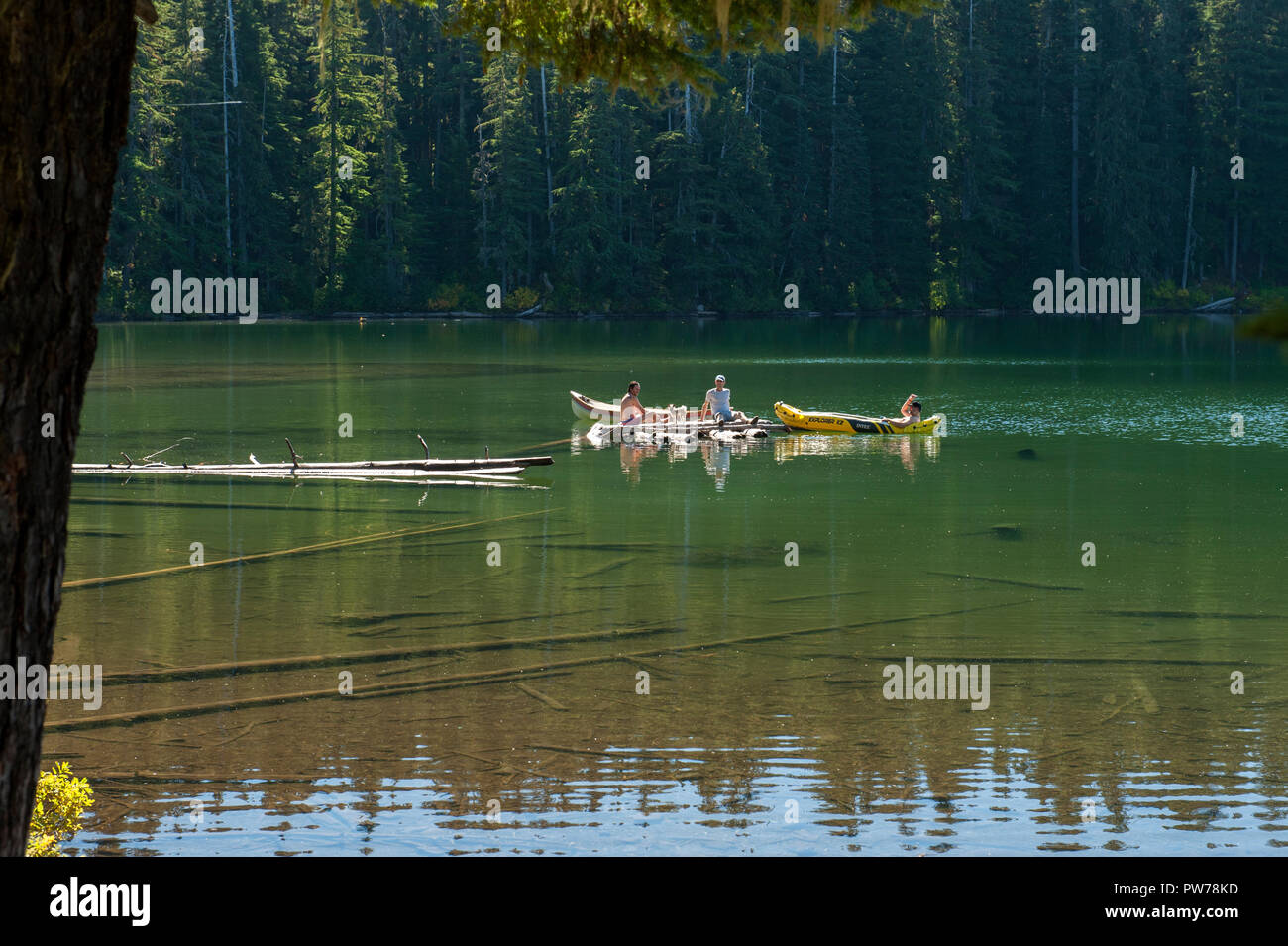 Trois jeunes gens non identifiés et un chien profiter les eaux de l'Oregon's Hideaway Lake au début de l'automne. Banque D'Images