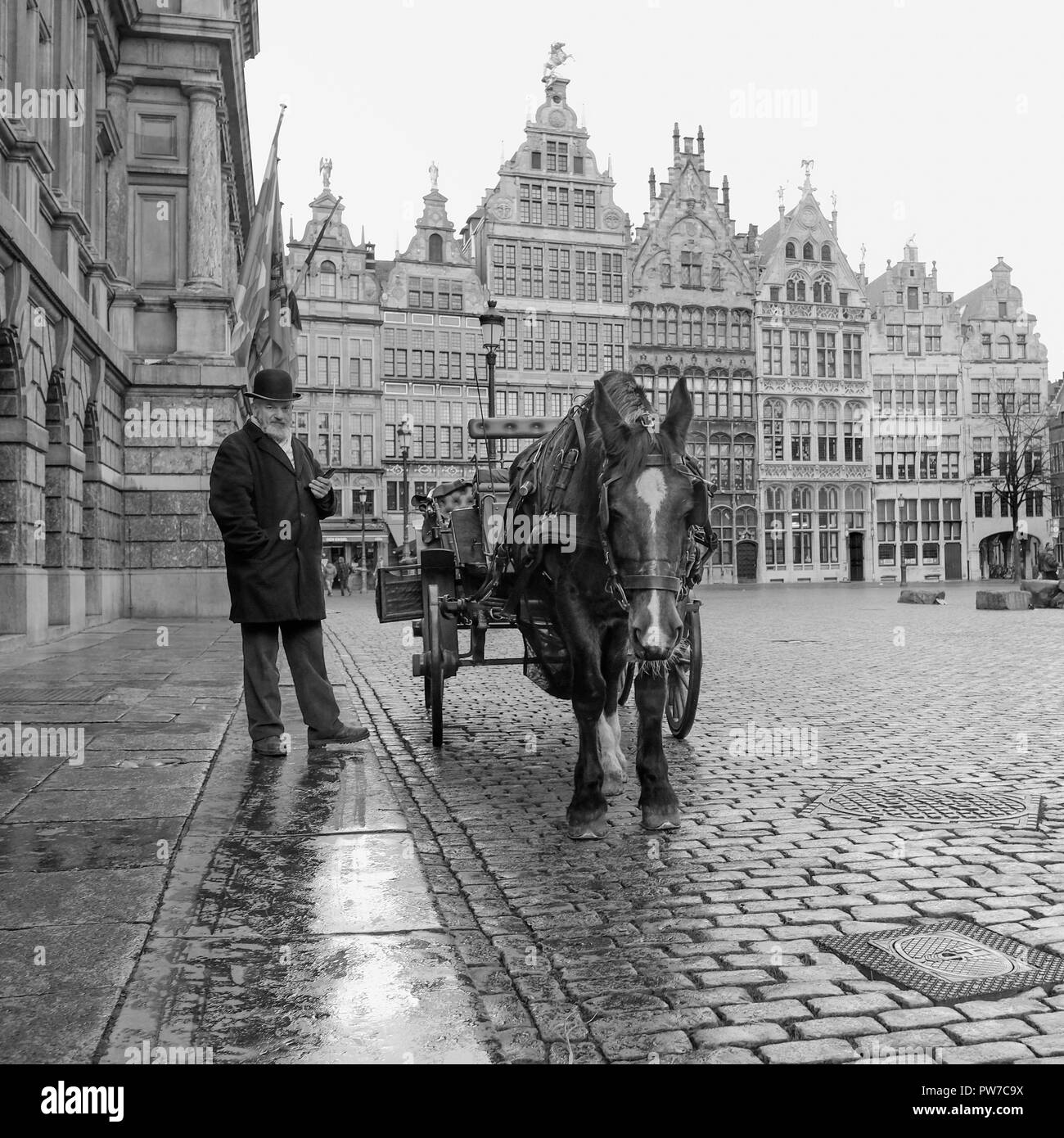 Image en noir et blanc de l'homme avec le panier et le cheval sur 'Historique Grote Markt' square à Anvers, Belgique. Banque D'Images