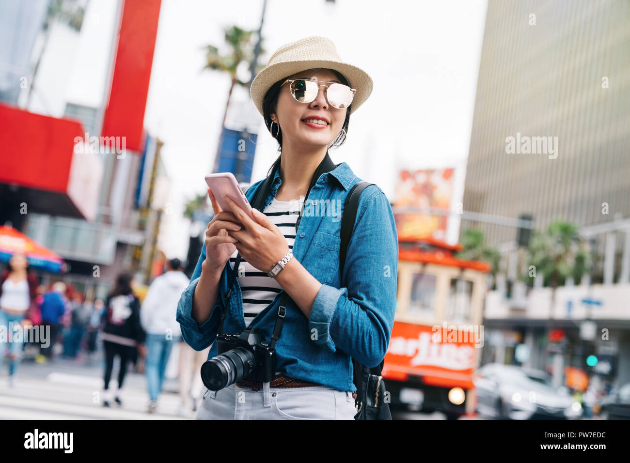 Femme attrayante à l'aide de voyageur son téléphone pour vérifier le sens à la place. Personne en visitant la veste jean femme objectif. Voyages au USA concept. Banque D'Images