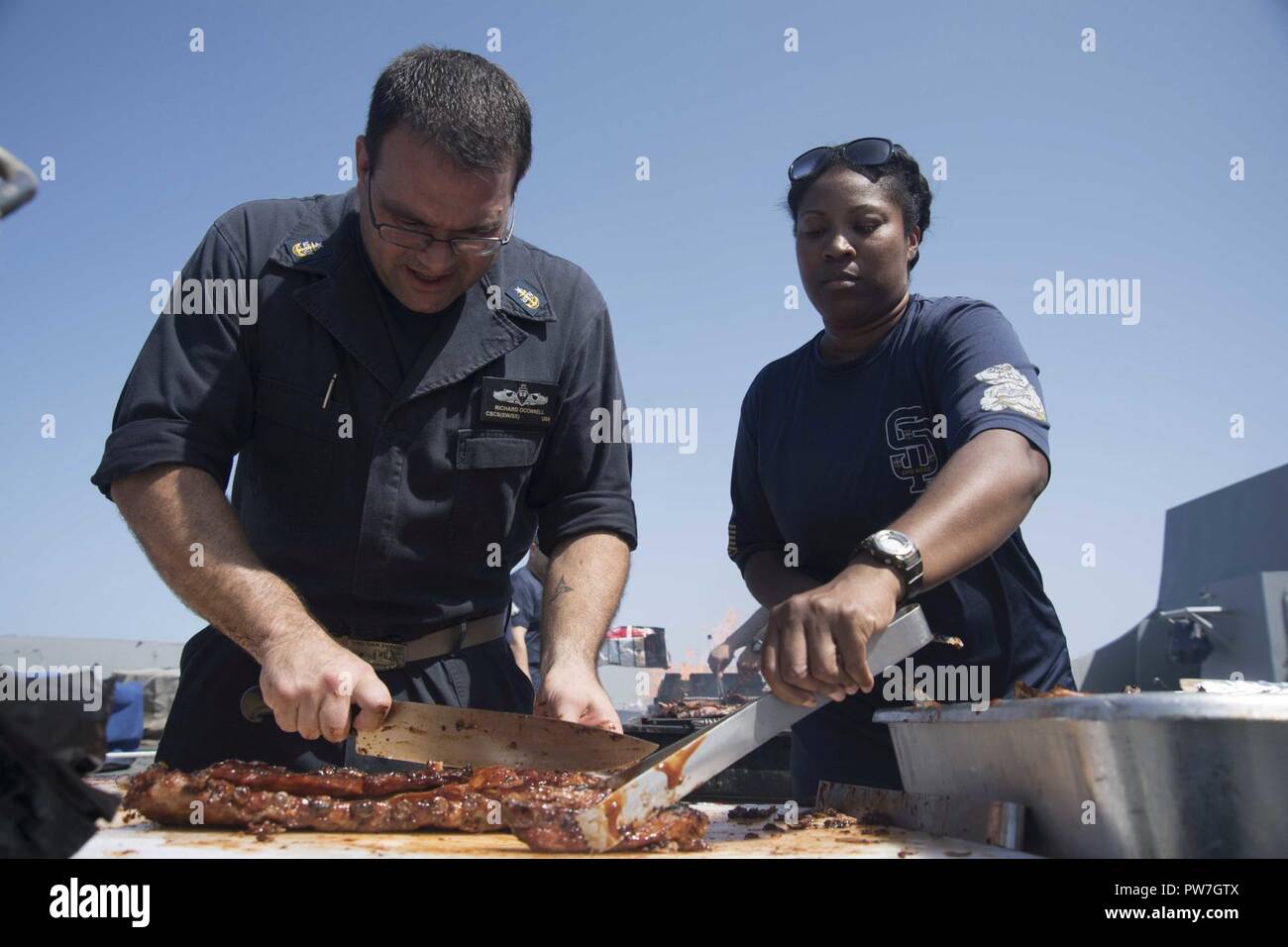 Mer Méditerranée (sept. 23, 2017) Le spécialiste culinaire Richard O'Connell, de Bristol, Rhode Island, à gauche, et le chef principal spécialiste des opérations Dawn Milton, de Detroit, de cuisiniers pour l'équipage lors d'un pique-nique sur la plage d'acier à bord du quai de transport amphibie USS San Diego (LPD 22) 23 septembre, 2017. San Diego est déployée avec l'Amérique latine groupe amphibie et le 15e Marine Expeditionary Unit à l'appui de la sécurité maritime et le théâtre de la coopération en matière de sécurité dans les efforts dans la sixième flotte américaine zone d'opérations. Banque D'Images