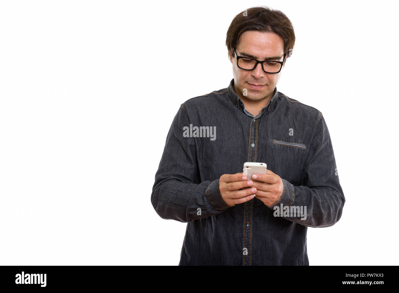 Studio shot of young man using mobile phone persan Banque D'Images