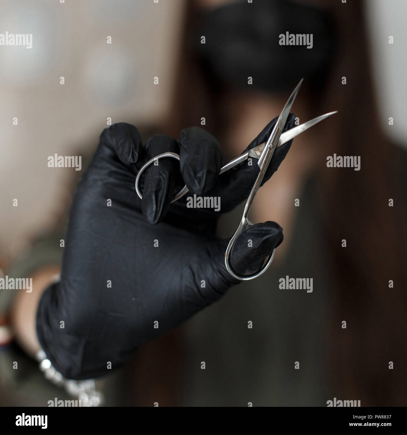 Ciseaux à ongles. Woman in Black gloves détient des ciseaux. Le soin des ongles Banque D'Images