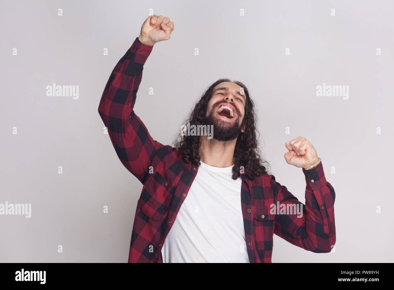 Oui je l'ai fait. Gagnant homme avec barbe et black long cheveux bouclés en chemise rouge à carreaux décontractée debout, criant et célébrer sa victoire Banque D'Images Oui je l'ai fait. Gagnant homme avec barbe et black long cheveux bouclés en chemise rouge à carreaux décontractée debout, criant et célébrer sa victoire Banque D'Images