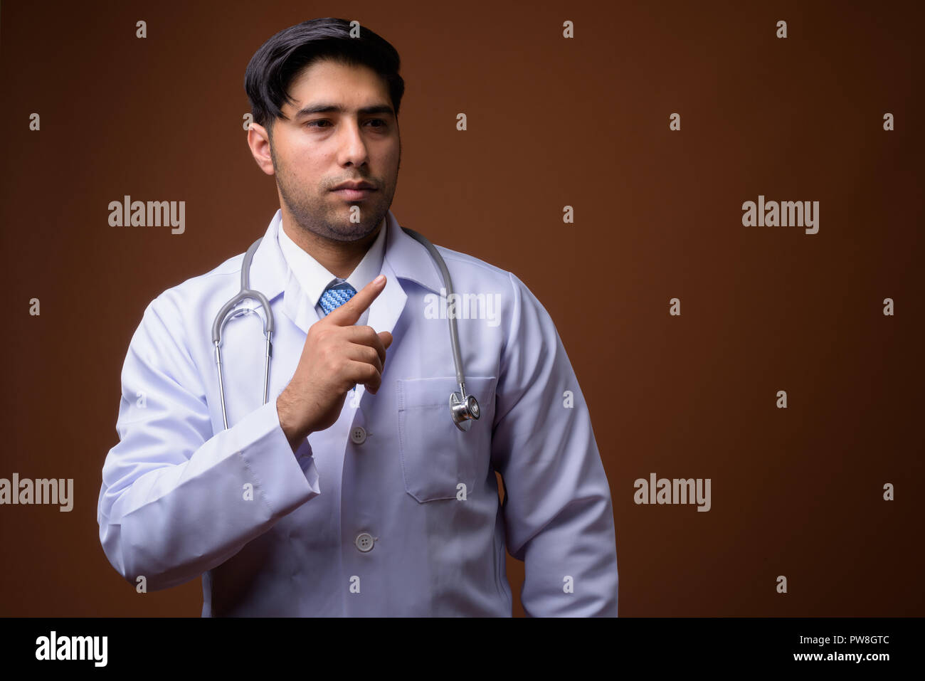 Beau jeune homme médecin iranien contre fond brun Banque D'Images