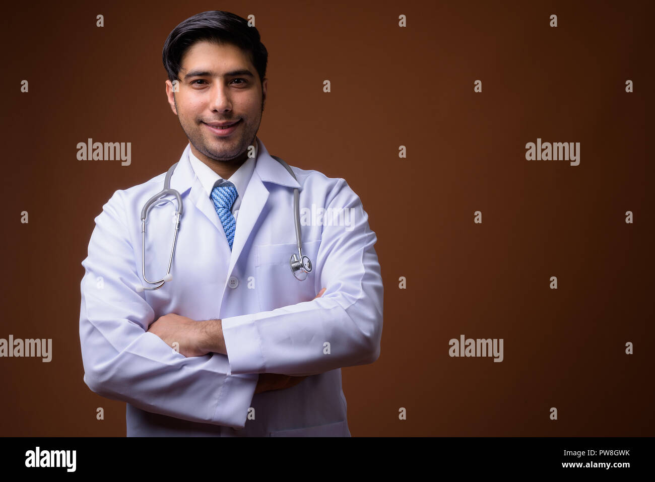 Beau jeune homme médecin iranien contre fond brun Banque D'Images