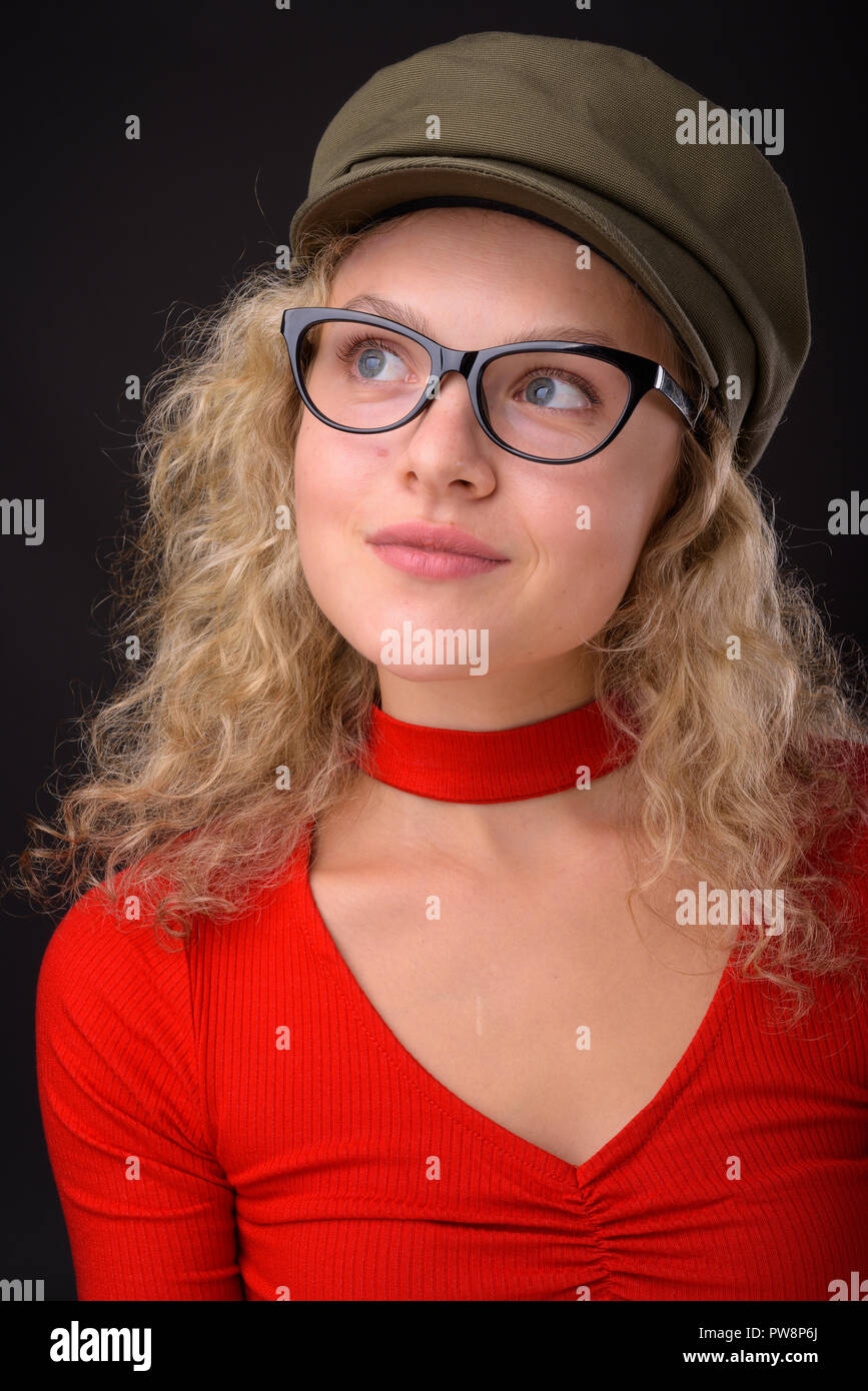 Belle jeune femme aux cheveux bouclés blonds contre gray background Banque D'Images