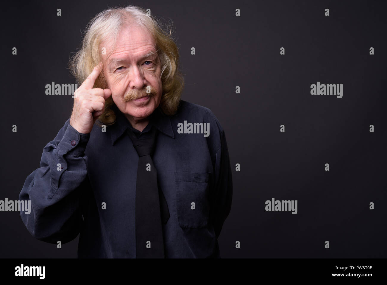 Senior businessman with moustache contre l'arrière-plan gris Banque D'Images