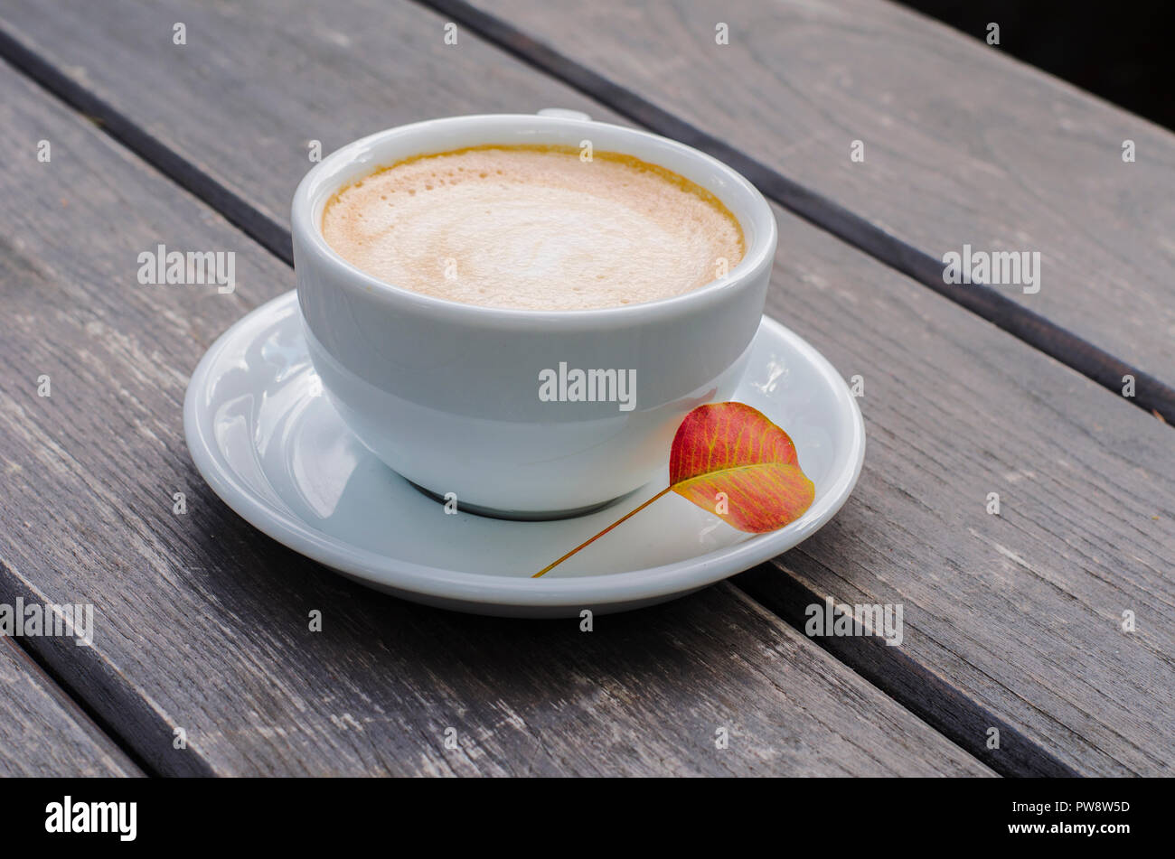 Tasse à café sur un fond de bois. La nature morte de latte avec les feuilles d'automne. Banque D'Images