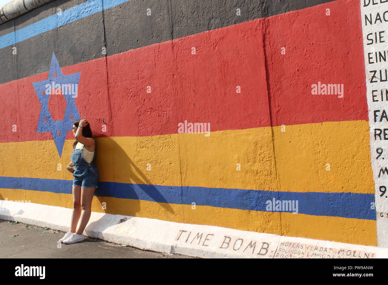 Girl reposant contre le mur de Berlin East Side Gallery Photo de l'allemand & drapeau israélien Banque D'Images