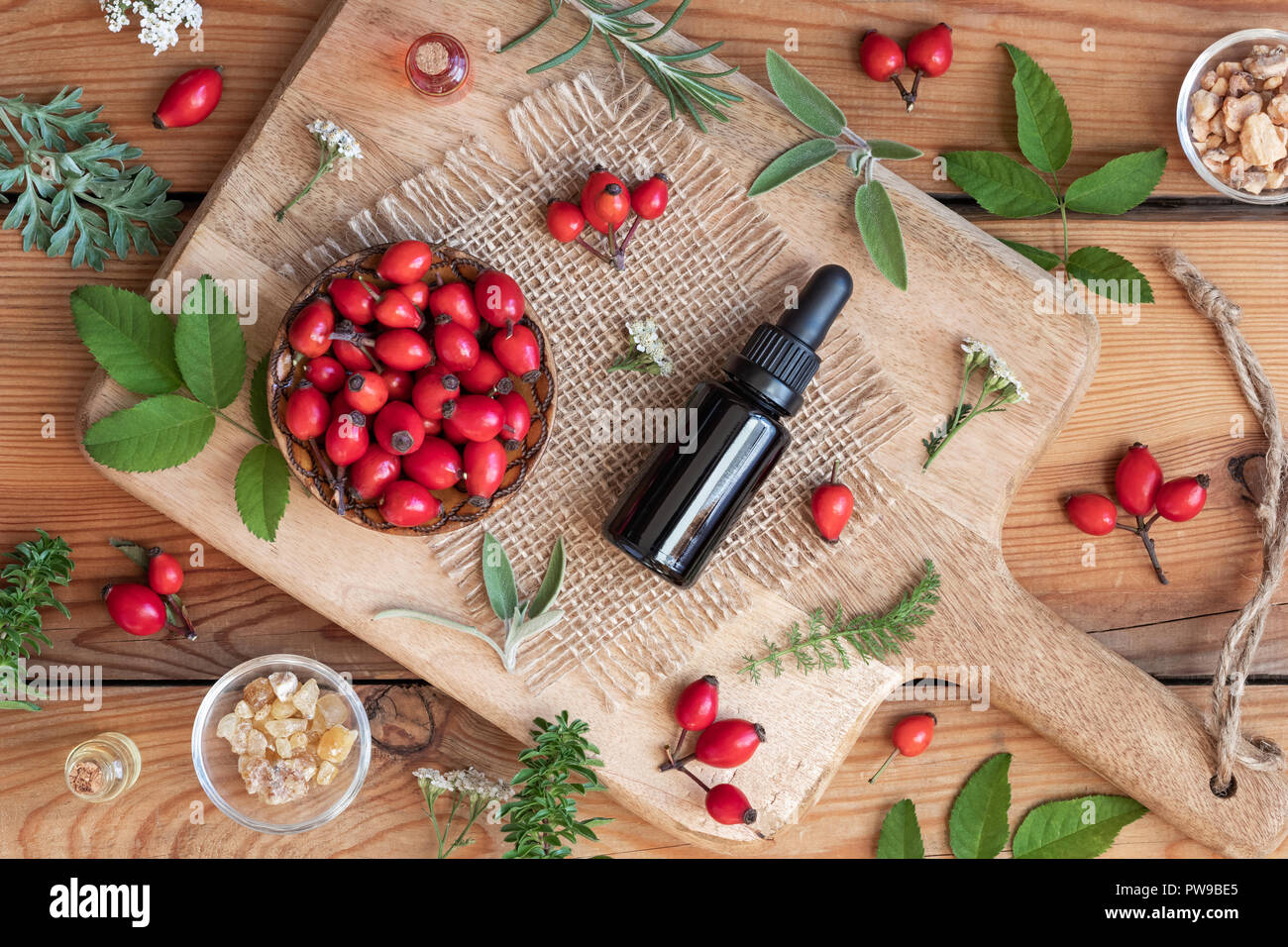 Une bouteille d'huile de graines de rose musquée avec sauge, absinthe, l'hiver savoureux et d'autres herbes on a wooden background Banque D'Images