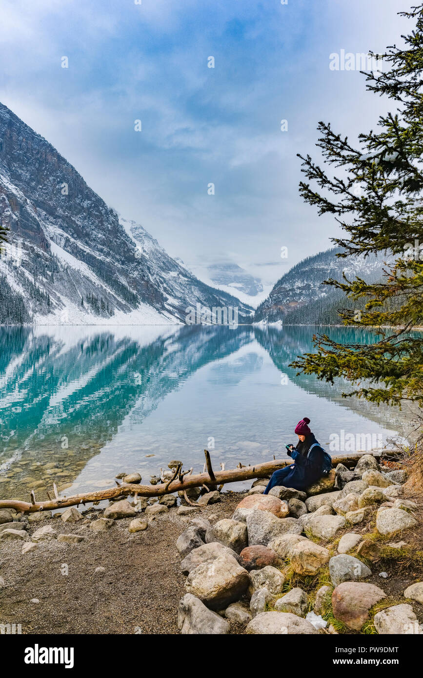 Young Asian woman looking at cell phone, hiver, Lake Louise, Banff National Park, Alberta, Canada Banque D'Images
