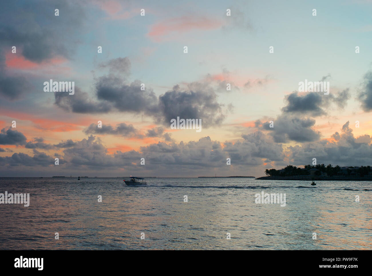 Soirée romantique Ciel avec nuages et Plae bleu, rose et orange Hues, de l'océan et un petit bateau de pêche à Key West, Florida, United States Banque D'Images
