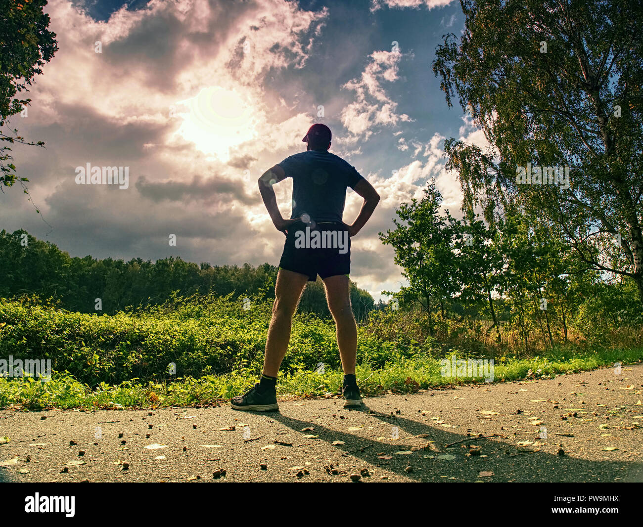 Haut de jogging homme sport dans les arbres d'ombre avec la lumière du  soleil derrière lui tout en portant un short noir jaune et bleu tenue de  jogging Photo Stock - Alamy