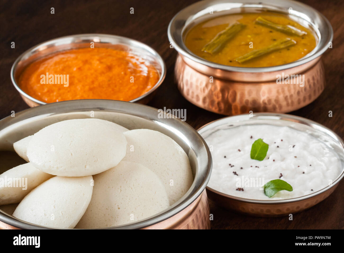 Les Indiens à la vapeur douce sans rien faire (Idli / gâteau de riz) disposés en cuivre authentique bol. Servi avec Chutney de tomates chutney de noix de coco, et des cochons. La lumière naturelle. Banque D'Images