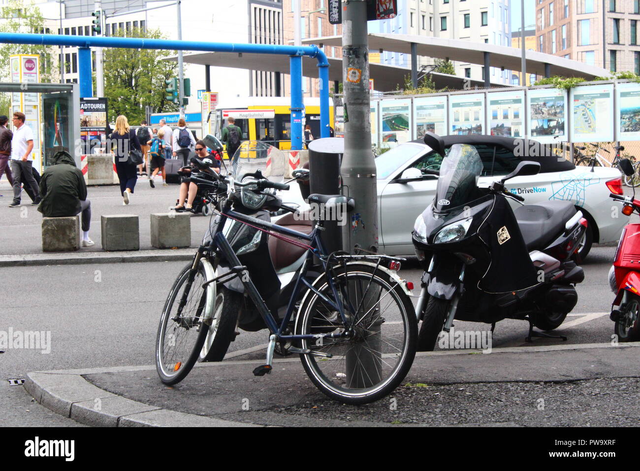 Vélo contre un lampost à Berlin, Allemagne avec un cyclomoteur à proximité et une voiture passant devant Banque D'Images