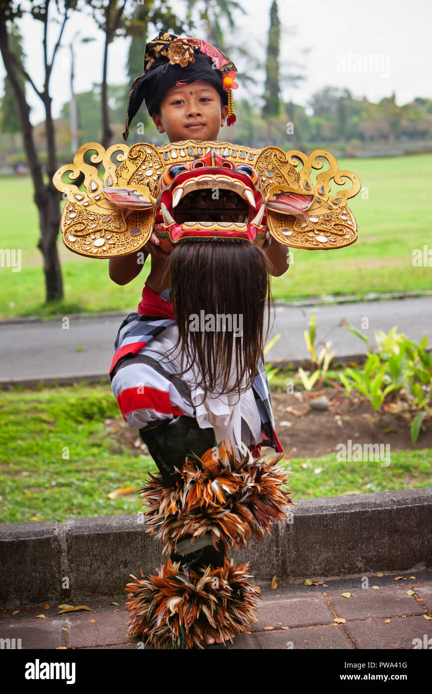 Bali, Indonésie - Juin 23, 2018 : Dancer boy en costumes ethniques avec masque traditionnel balinais de bon esprit Barong sur Ngelawang cérémonie hindou Banque D'Images