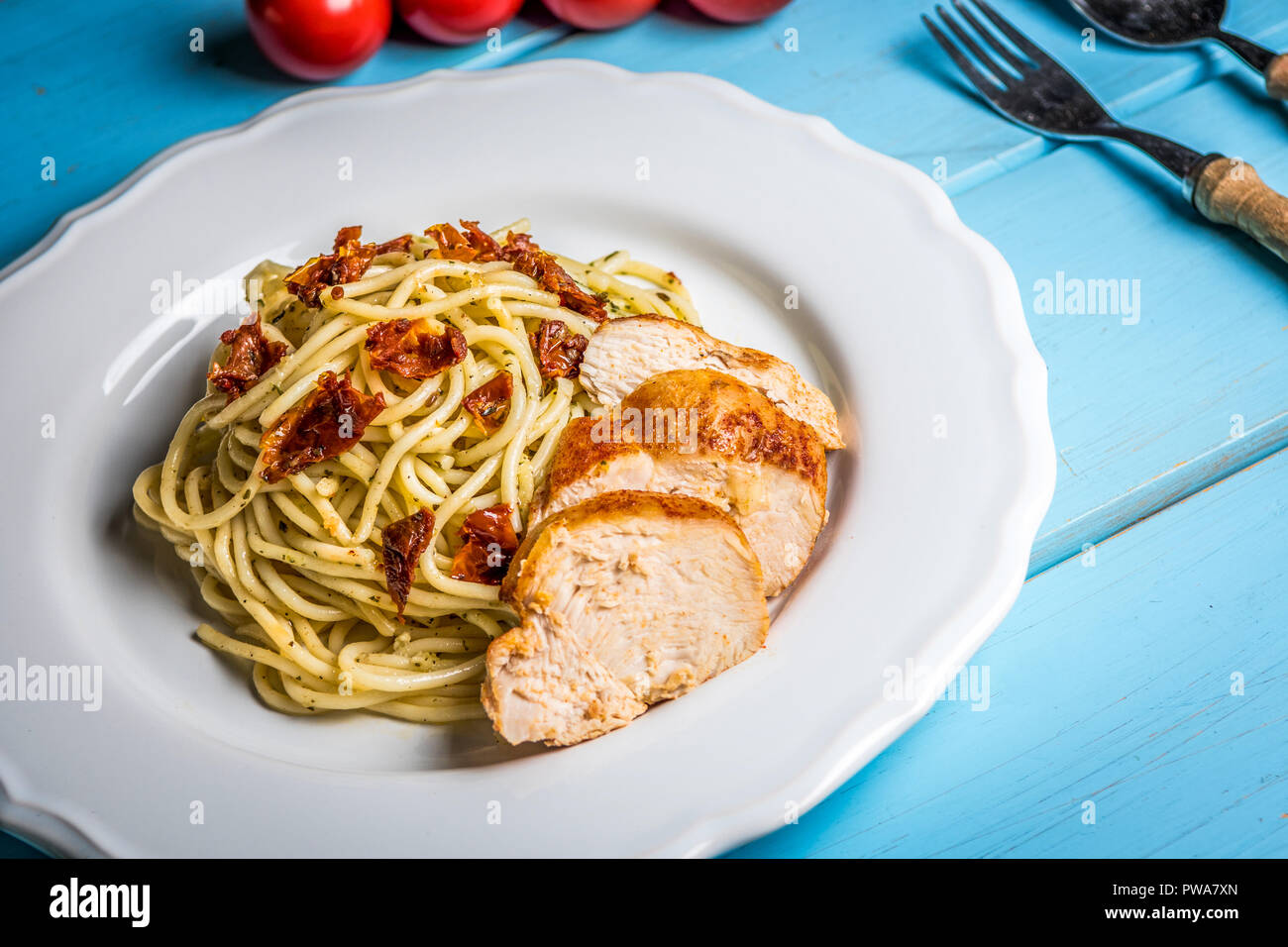 Spaghetti pâtes italiennes avec du poulet, tomates séchées et basilic Pesto sur tableau bleu Banque D'Images