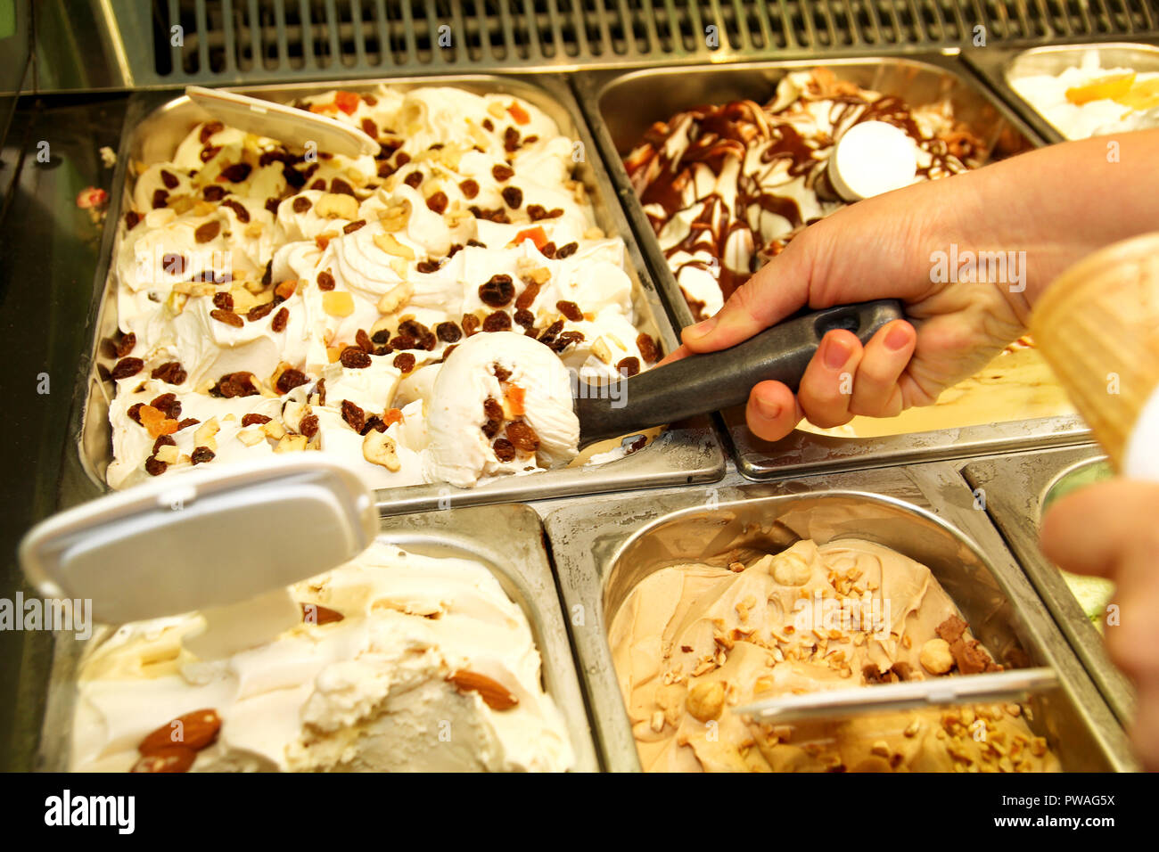 La main féminine avec boule de crème glacée dure du réfrigérateur et servir en cornet gaufré. Femme qui écope de la crème glacée savoureuse. Réfrigérateur avec de la glace. Banque D'Images
