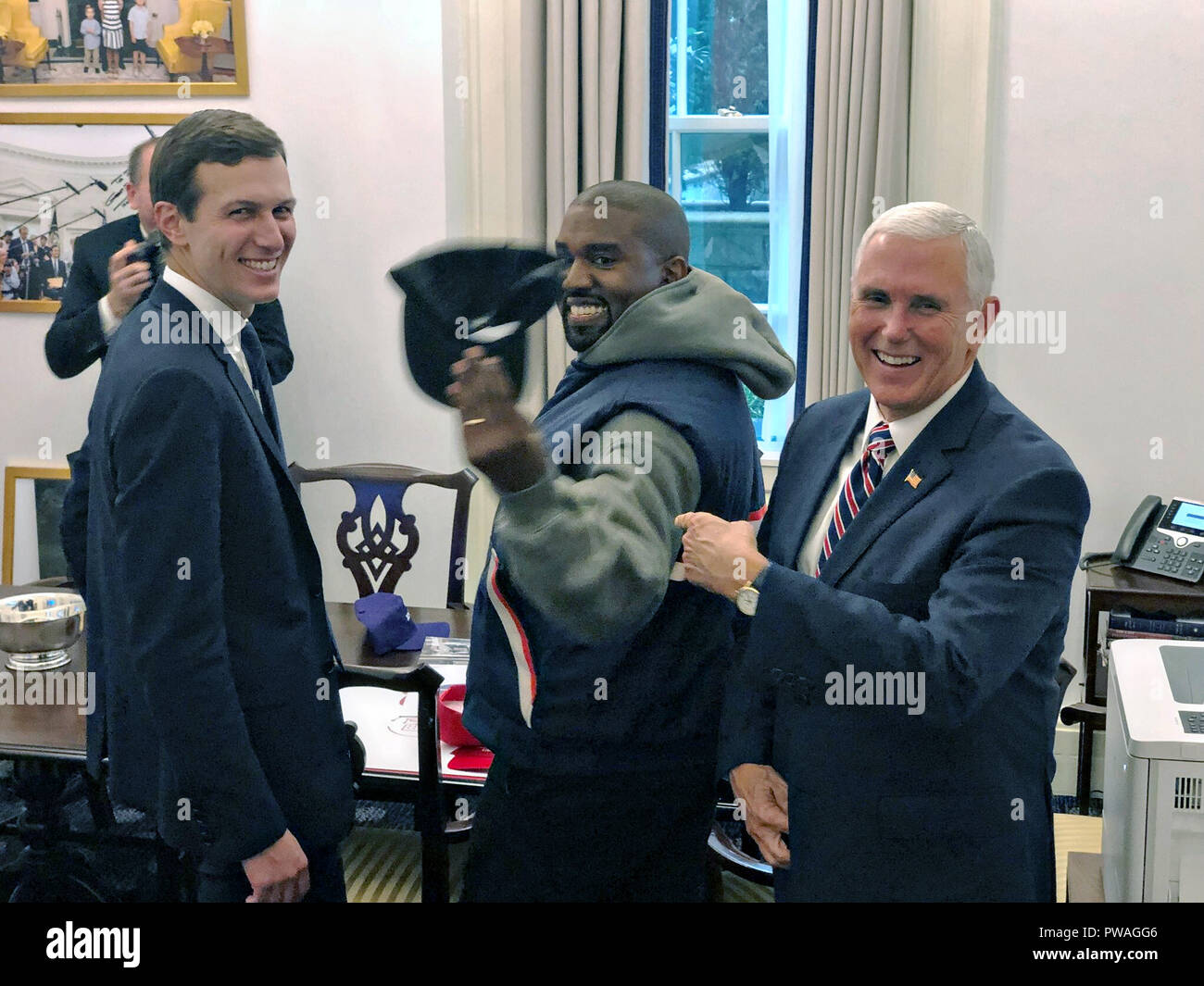 Le Vice-président américain Mike Pence rire blagues qu'il interprète avec Kanye West, centre, en tant que conseiller présidentiel Jared Kushner, gauche, regarde dans l'avant-Bureau ovale de la Maison Blanche le 11 octobre 2018 à Washington, DC. Banque D'Images