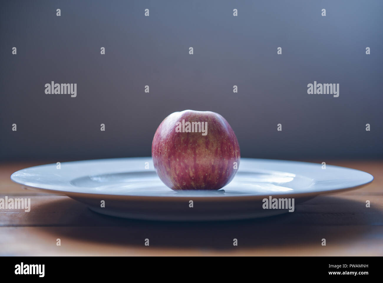 Vue latérale d'une pomme rouge dans le milieu de la plaque blanche avec fond noir Banque D'Images