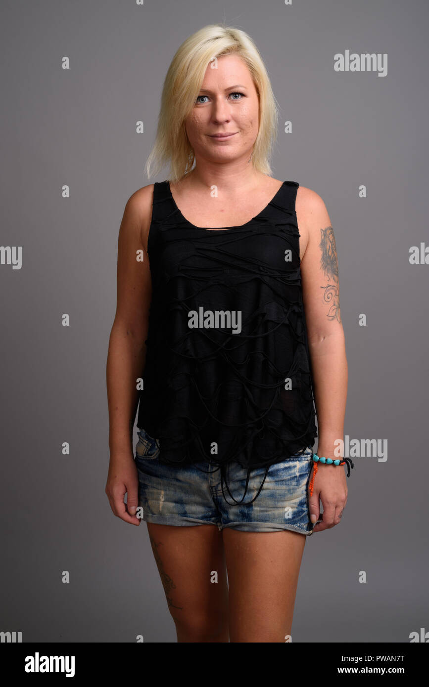 Portrait de femme aux cheveux blonds contre l'arrière-plan gris Banque D'Images